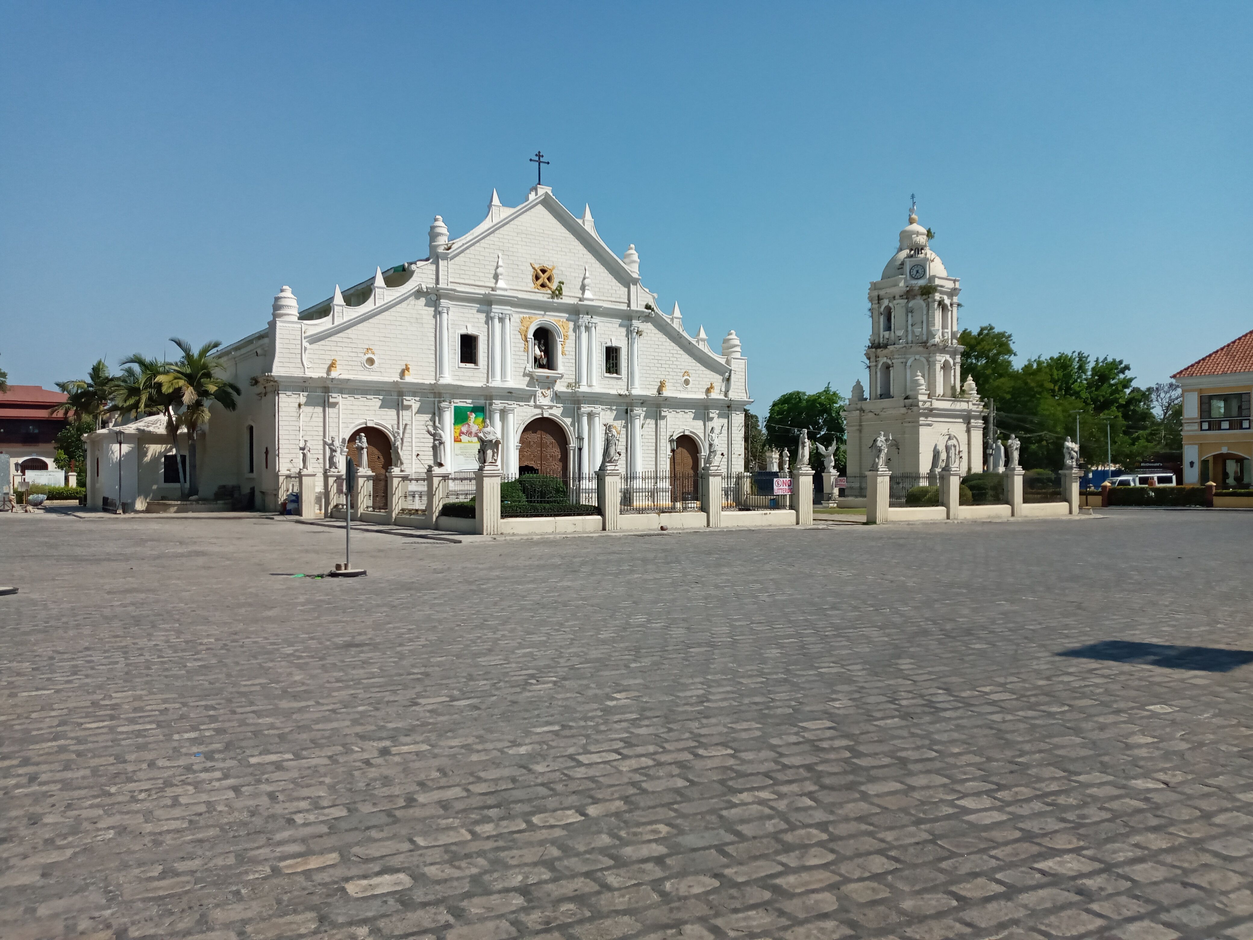 The white façade of St. Paul Cathedral and its detached bell tower across the cobbled plaza.